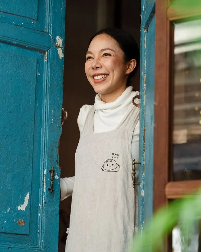 A café owner smiling in her doorway
