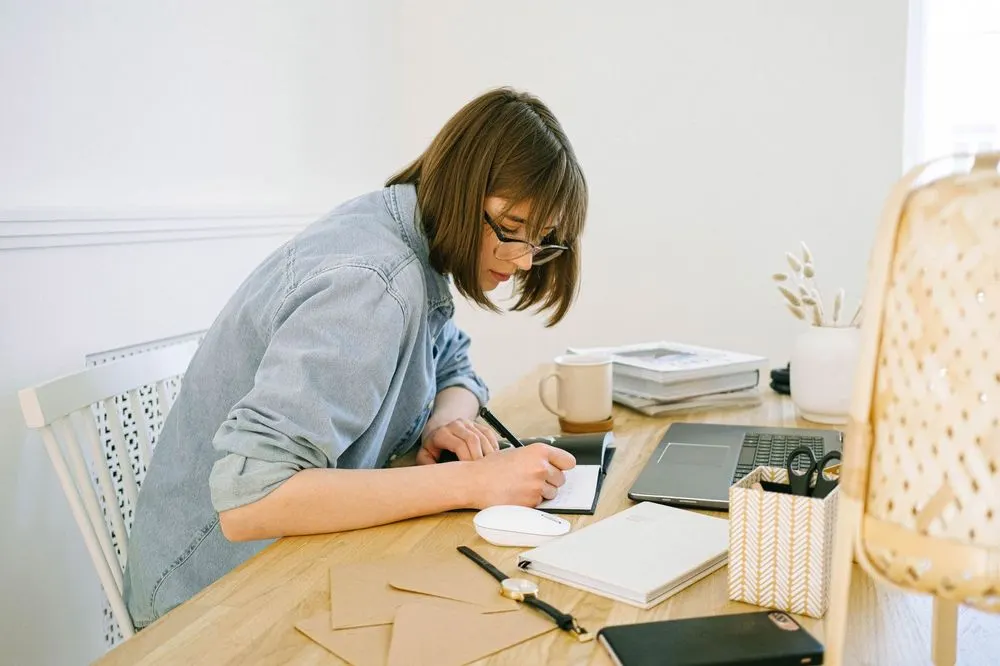 A woman writing in her planner at a tidy desk