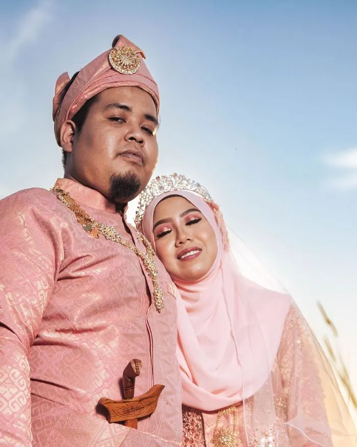 A bride and groom in traditional Malay wedding clothes